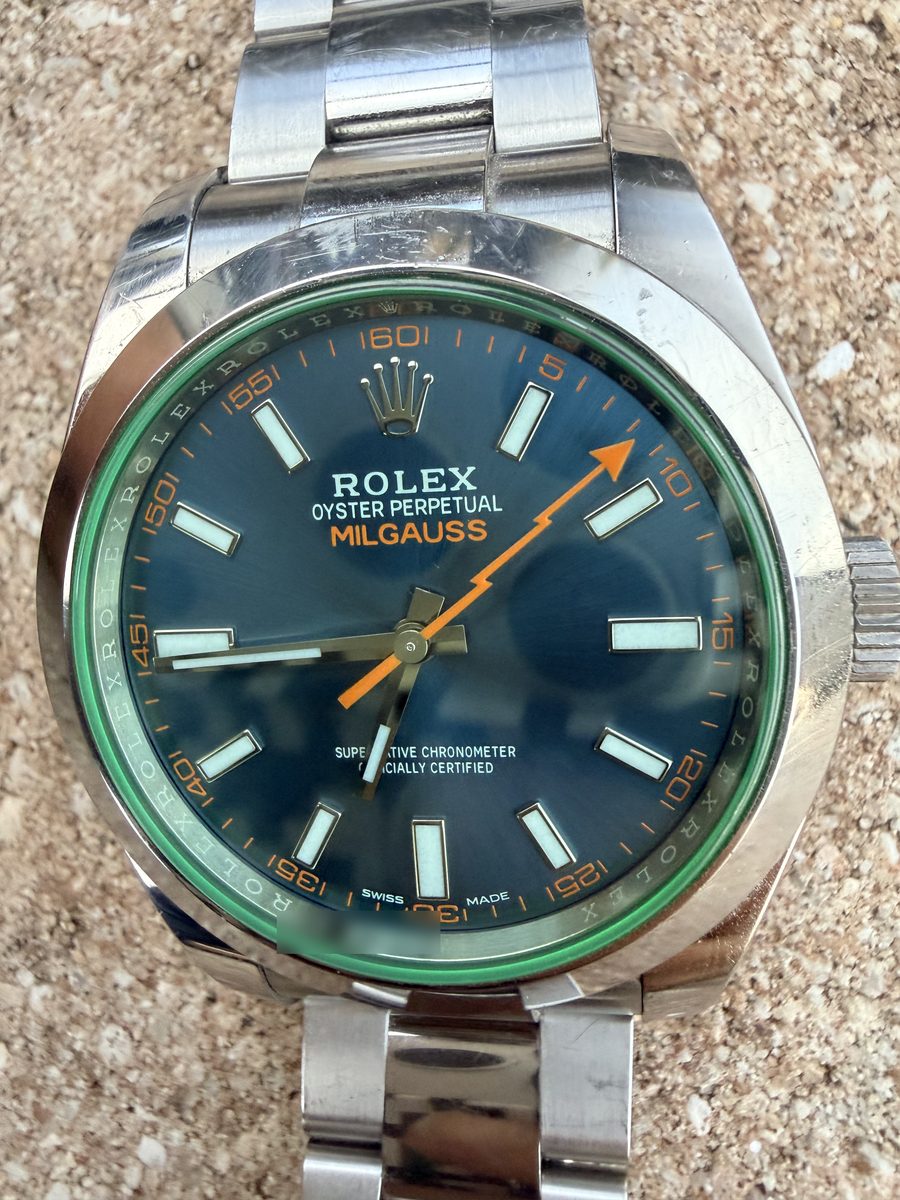 Close on the dial of a steel Rolex Milgauss: blue dial, orange lightning-bolt seconds hand, green-tinted crystal, photographed by its owner
